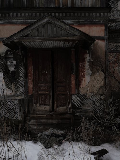 Exterior of aged abandoned house with damaged walls and old timber weather door