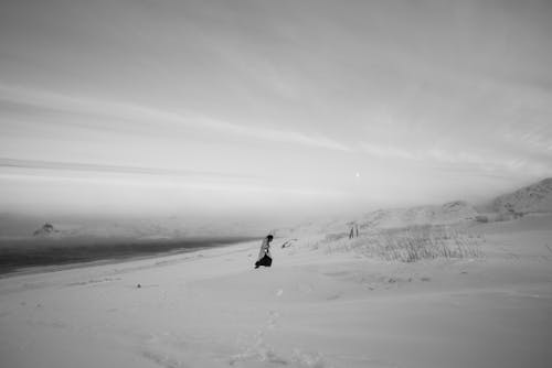 Free A Person Walking on a Snow Covered Ground in Black and White Photography Stock Photo