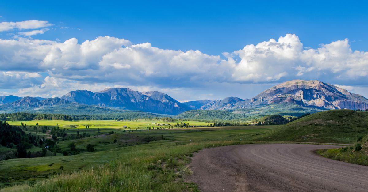 Breathtaking landscape of mountains and fields under a vibrant blue sky in Pagosa Springs, Colorado.