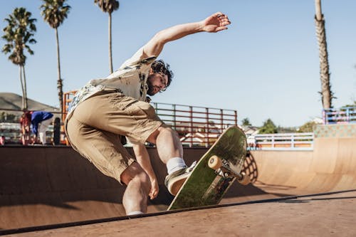 Man in Brown Shorts and Black Shirt Sitting on Skateboard