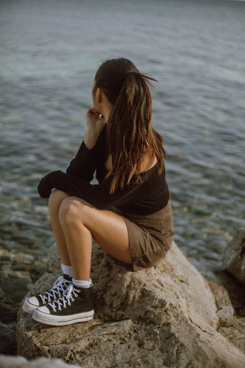Free Woman in Black Long Sleeves while Sitting on a Big Rock Stock Photo