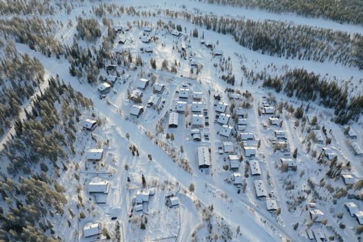 A drone view capturing snow-covered homes and trees in a Swedish village during winter.