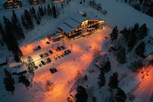 Aerial view of a winter resort in Älvdalen lit at night with parked cars and snowy trees.