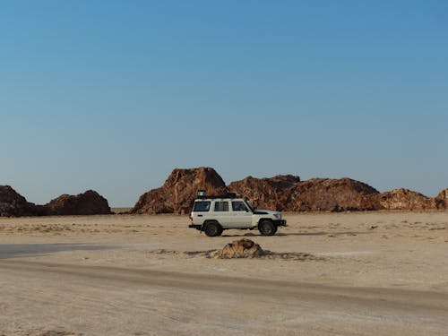 Free White SUV Parked on Brown Sand of a Desert Stock Photo