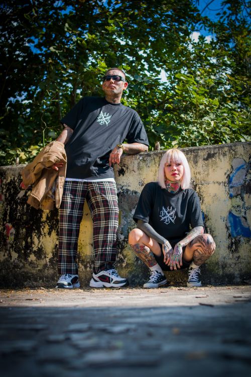 Free Fashionable couple with tattoos poses in stylish outfits in a vibrant outdoor setting. Stock Photo