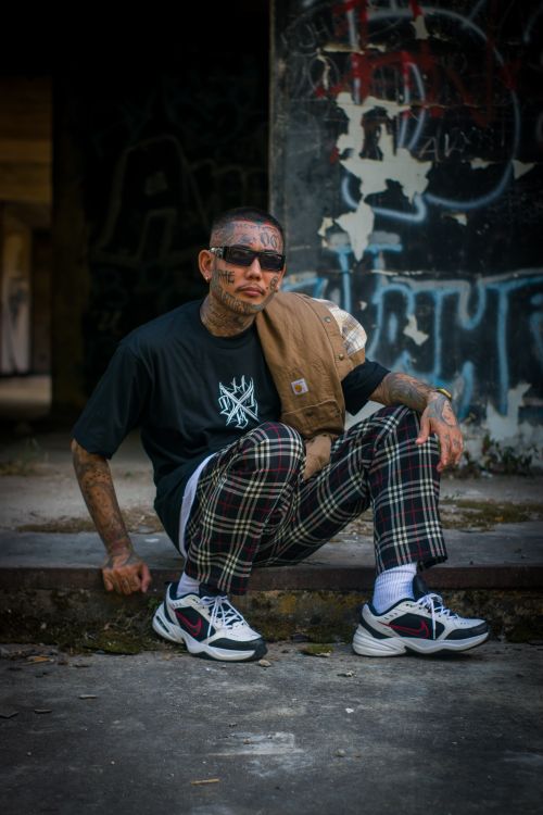 Free Stylish tattooed man in urban setting wearing sunglasses and plaid pants. Stock Photo