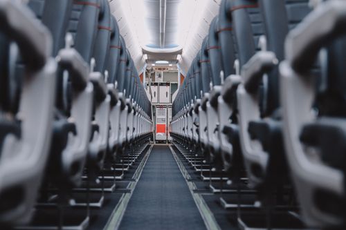 Free Symmetrical view through an empty airplane cabin showcasing rows of blue seats. Stock Photo