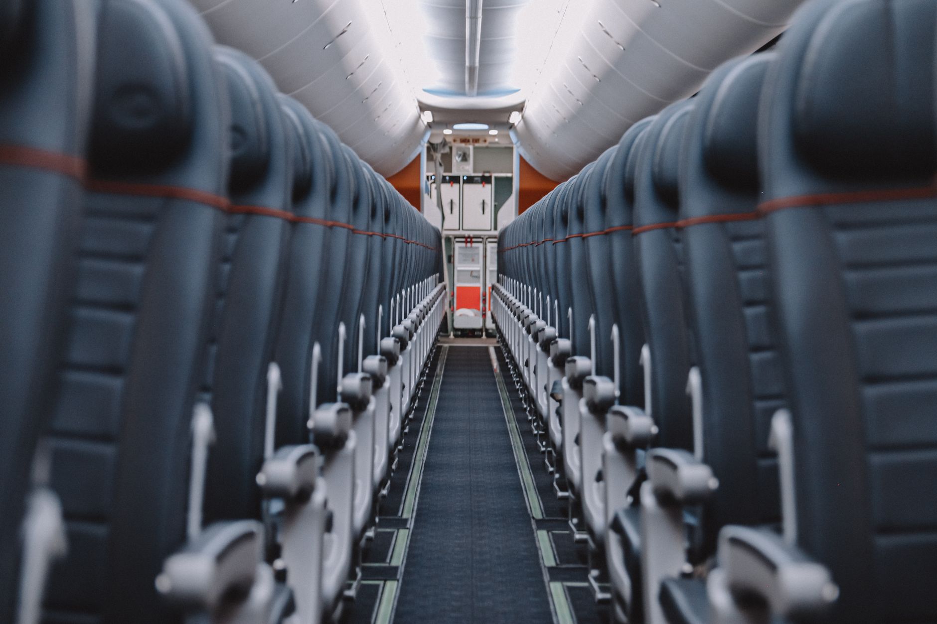 View down the aisle of an empty airplane cabin showcasing seats and overhead compartments.