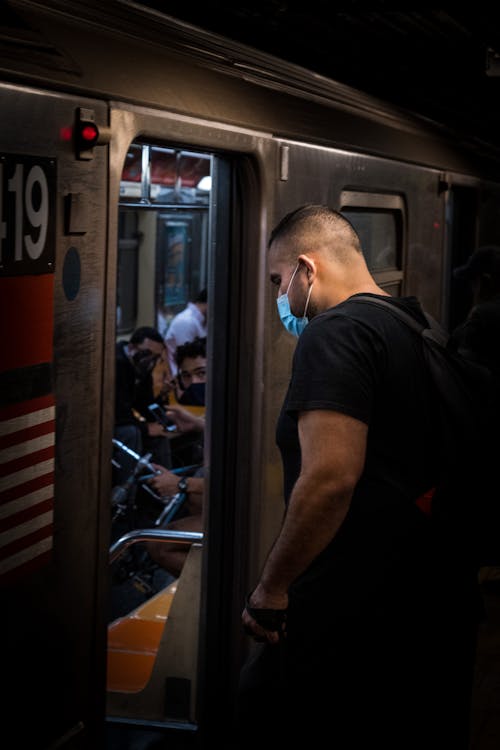 A Man Wearing Face Mask Riding a Train