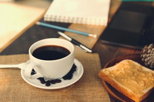 Free Cup and Saucer of Black Coffee Near a Bread Stock Photo
