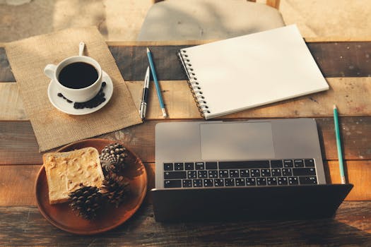 A warm, inviting home office workspace with a coffee cup, laptop, and notepad on a wooden table.