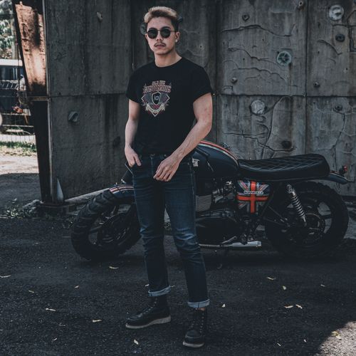 Free A man wearing sunglasses poses beside a custom motorcycle outdoors. Stock Photo