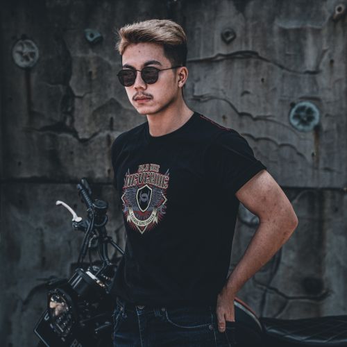 Free Young man in sunglasses posing with a motorcycle against a grungy concrete wall. Stock Photo