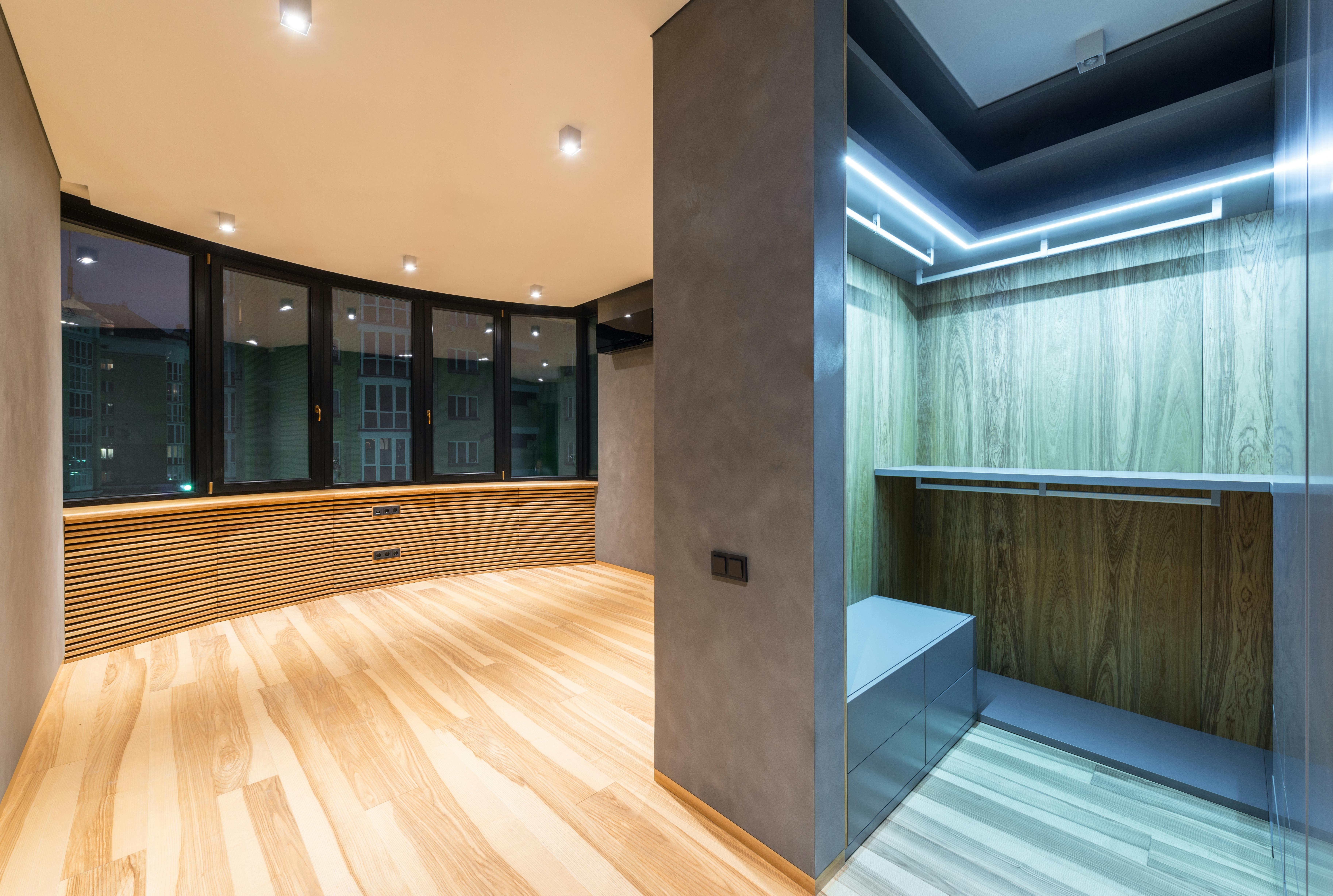 Free Creative design of empty room interior with wardrobe against windows under shiny lights in flat with parquet Stock Photo