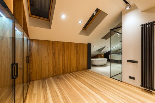 Creative design of bathroom with bath on floor under windows illuminated by lamps in house