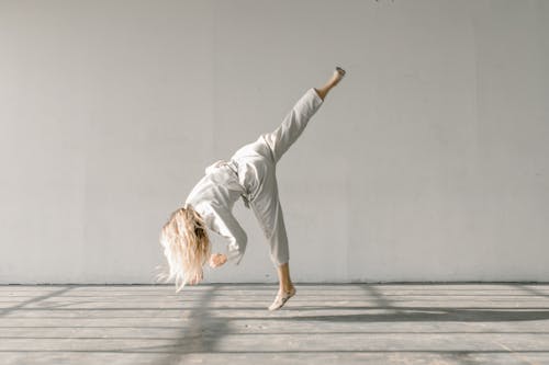 A Woman in White Gi Training in the Gym