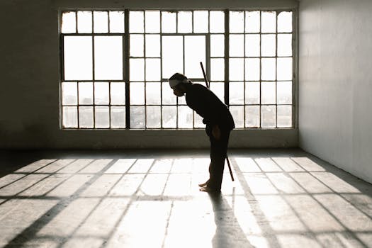 A martial artist bows gracefully in a sunlit room, symbolizing respect and discipline.