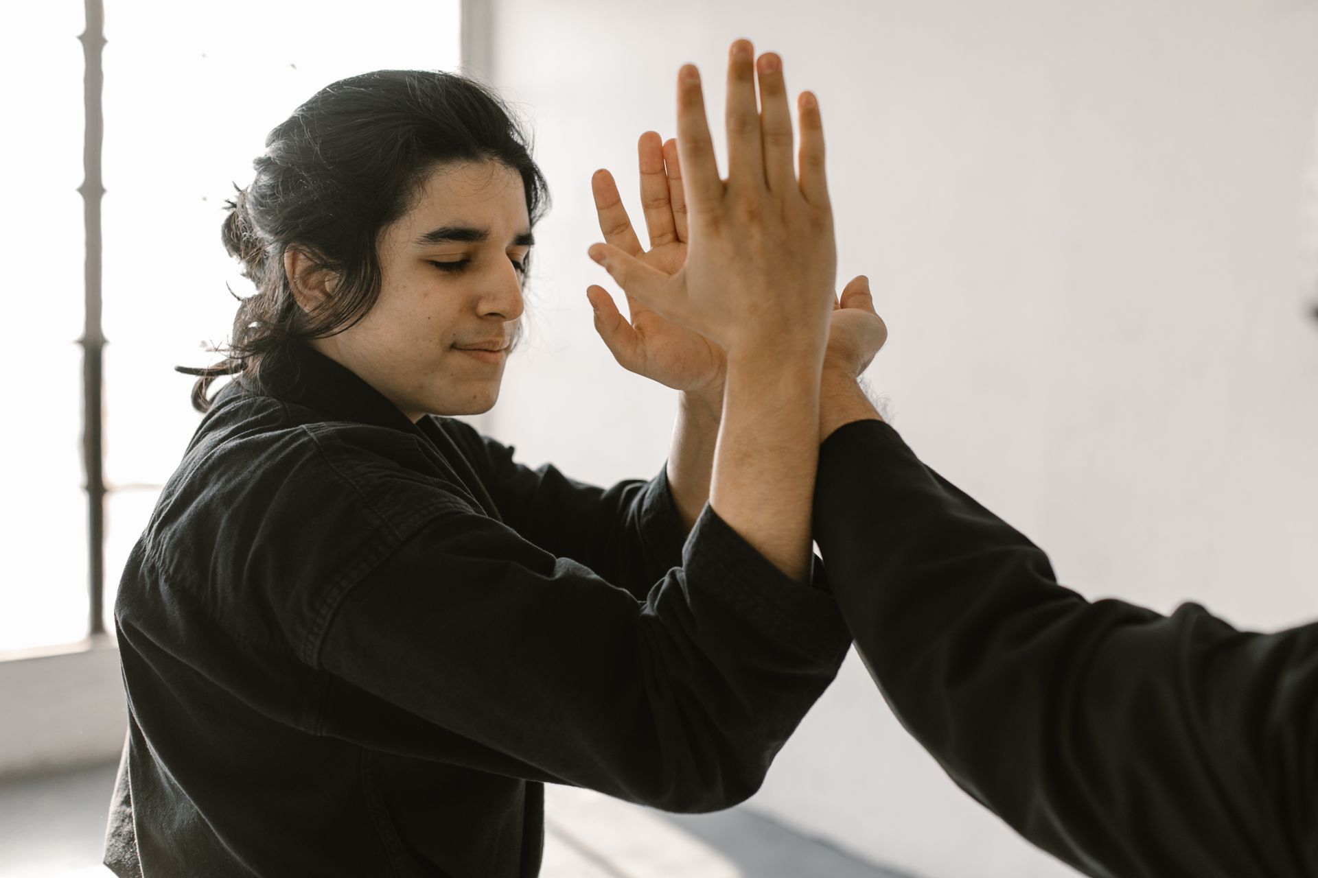 Two martial artists practicing techniques indoors with focus and precision.