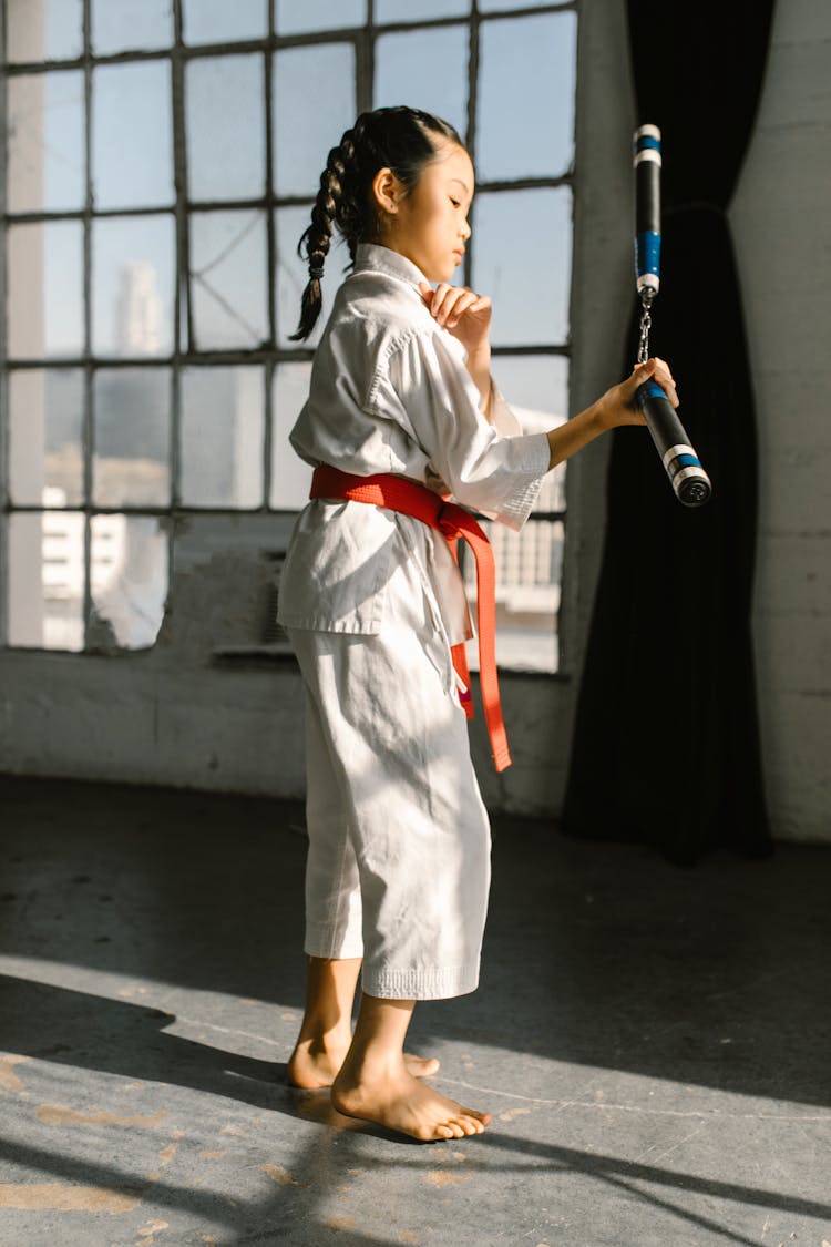 Girl In Taekwondo Uniform Using Karate Sticks