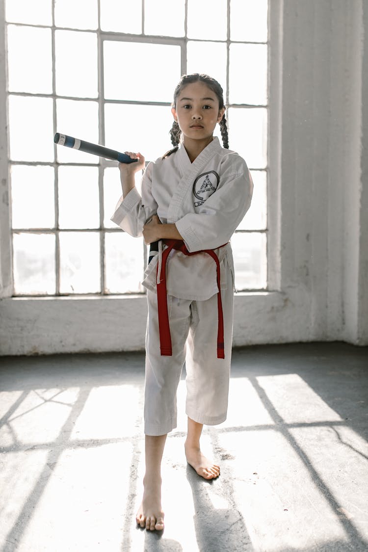 A Girl In White Gi Holding Nunchaku