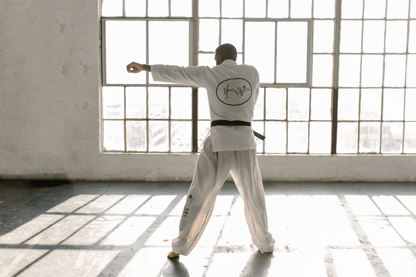 Adult karate practitioner training striking technique in a bright dojo.