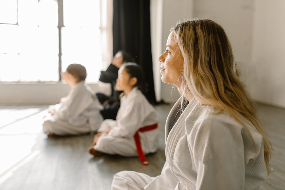 Woman in White Taekwondo Uniform Sitting on the Floor