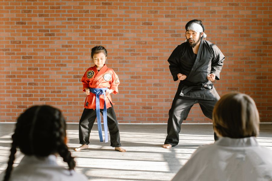 A martial arts instructor and a young student in a ready stance in a dojo