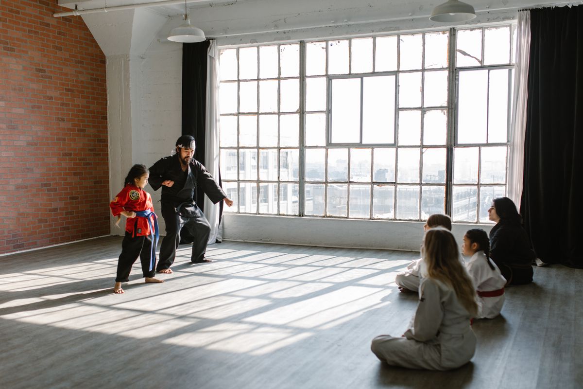 Martial arts instructor coaching a child during structured training.