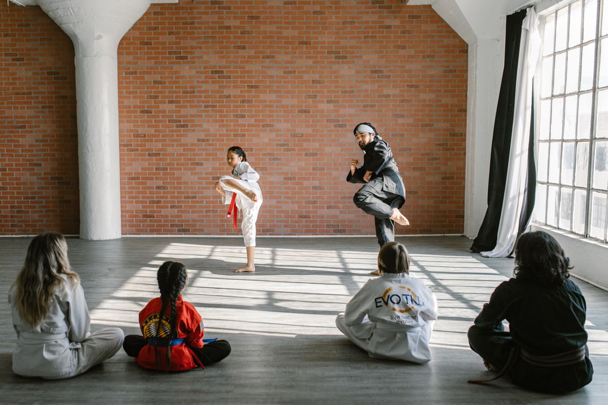 Child practising controlled martial arts technique with an instructor.