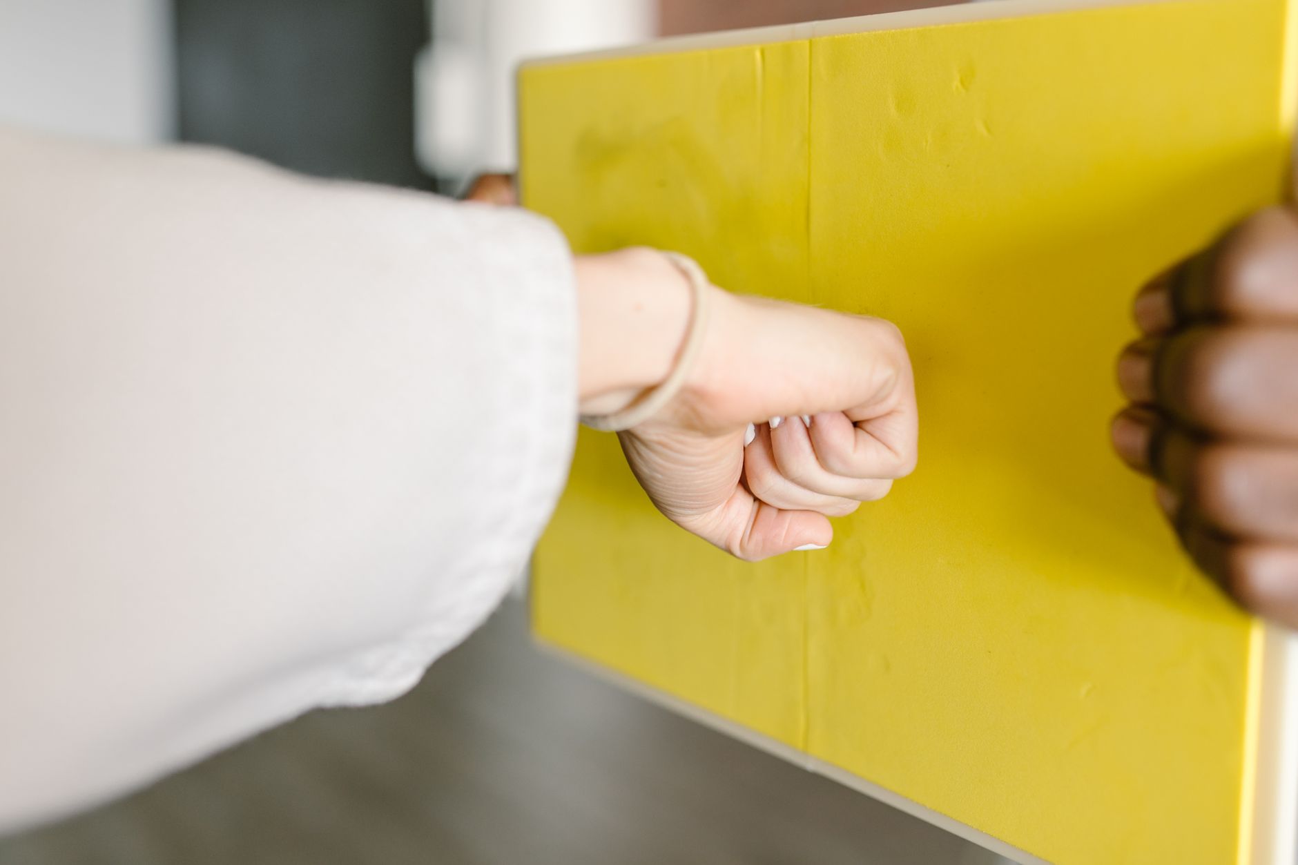 How Karate Builds Leadership Skills Through Discipline 4 Close-up of a fist punching a yellow martial arts rebreakable board indoors.