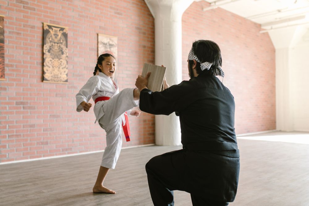 Young student practicing a kick with her instructor
