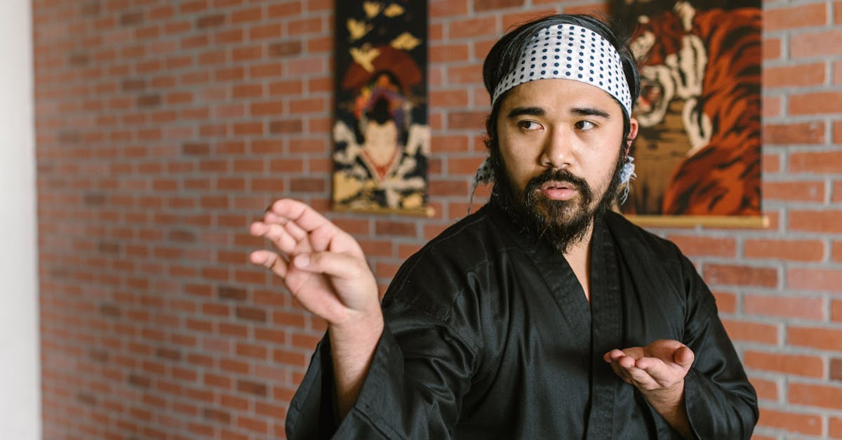 A focused martial artist in a black gi practicing a martial arts pose indoors.
