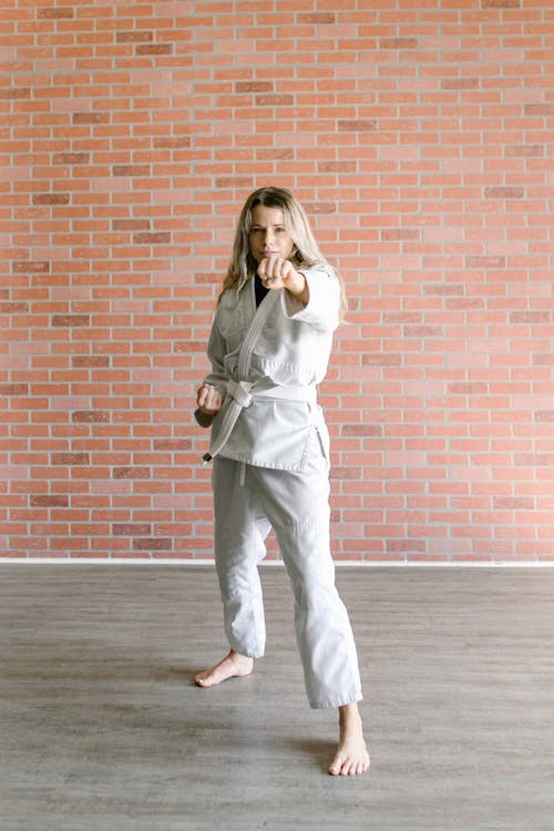 Free A Woman in Taekwondo Uniform while Standing Near the Brick Wall Stock Photo