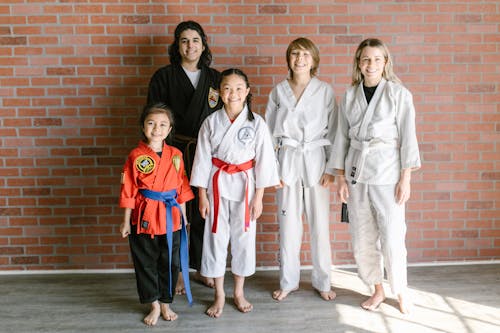 A Group of People in Taekwondo Uniform Standing Near the Brick Wall