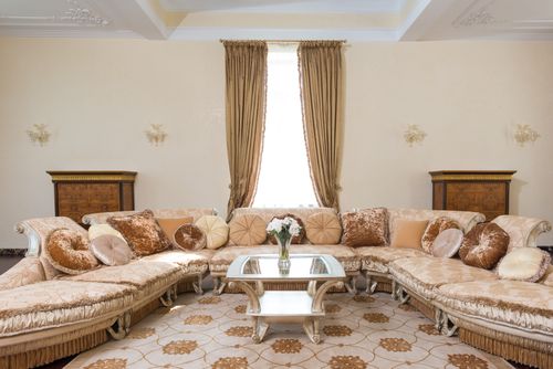 Free Interior of comfortable spacious living room with soft pillows on long couch and glass table with vase filled with flowers Stock Photo