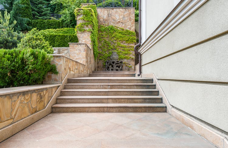 Concrete Steps Of Building With Yard Decorated With Green Bushes