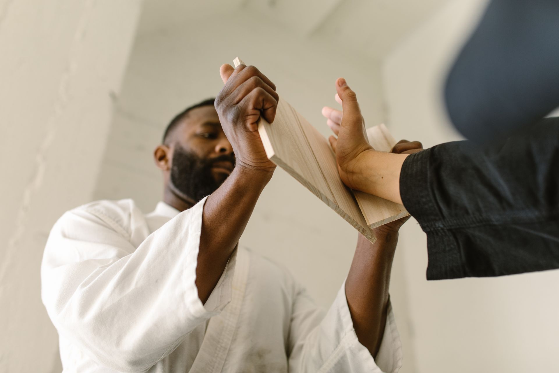 Martial artist breaking a board during training in dojo. Intense focus and skill.