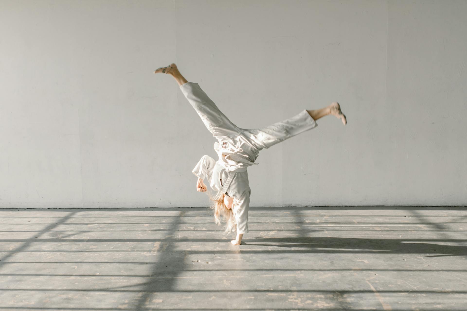 A Woman in White Gi Doing Handstand