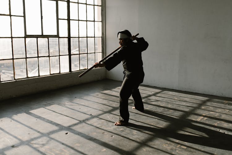 Man In Black Karate Uniform Holding A Stick