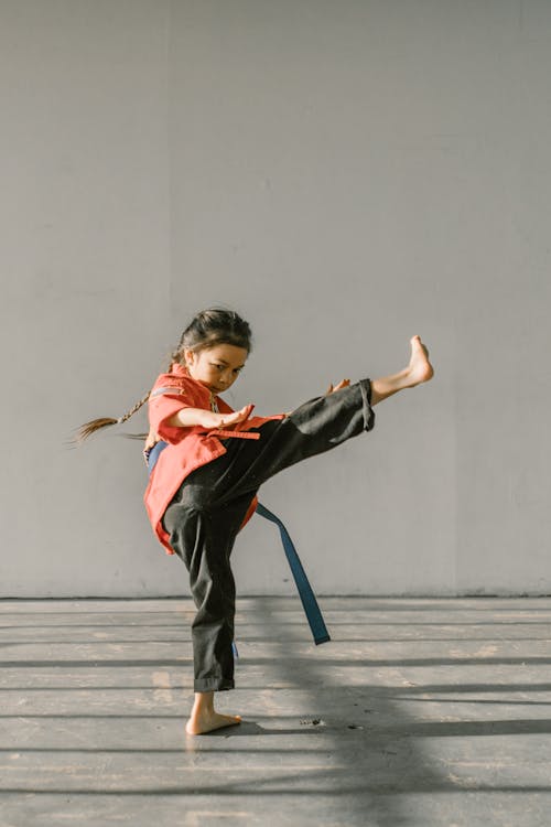 Free Man in Red and Black Jacket and Black Pants Jumping on Gray Concrete Floor Stock Photo