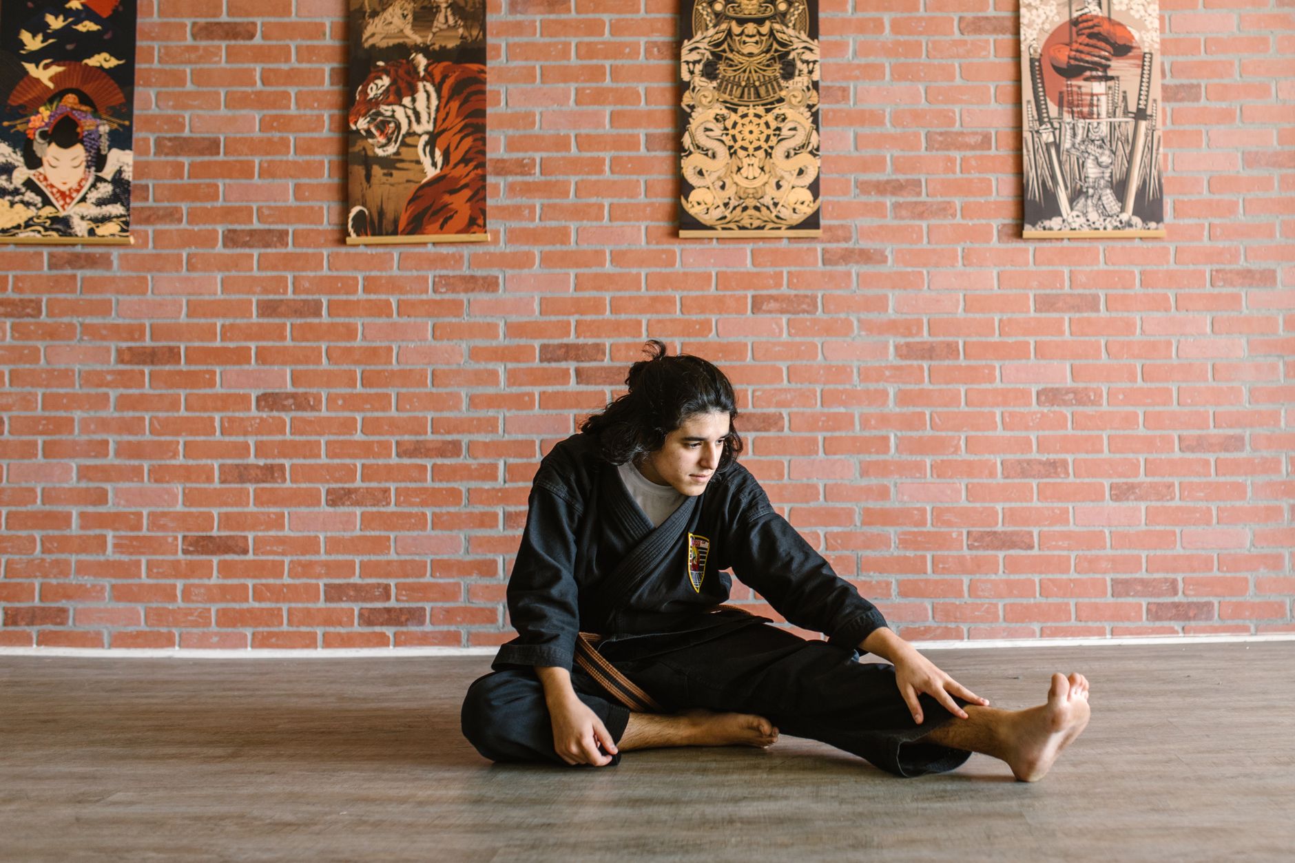 How To Increase Your Sex Drive Naturally 1 Martial artist in black gi stretches on dojo floor with artistic decor on brick wall.
