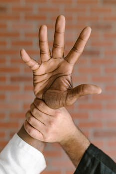 Close-up of a martial artist demonstrating a defensive hand technique against a brick wall.