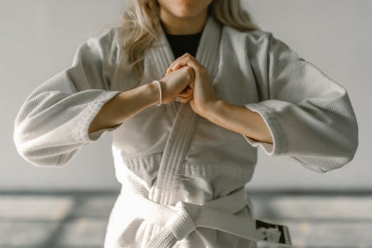 Close-up of a karate practitioner in white gi performing a hand gesture indoors.
