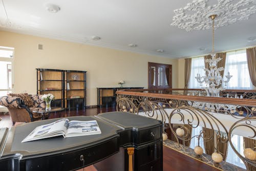 Interior of classic luxurious flat with black shelves and huge chandelier hanging on white ceiling