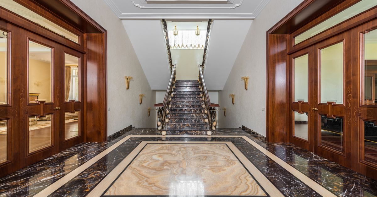 Interior of spacious corridor with marble floor and stairway in luxury apartment in daylight