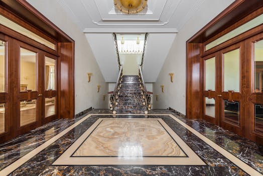 Interior of spacious corridor with marble floor and stairway in luxury apartment in daylight