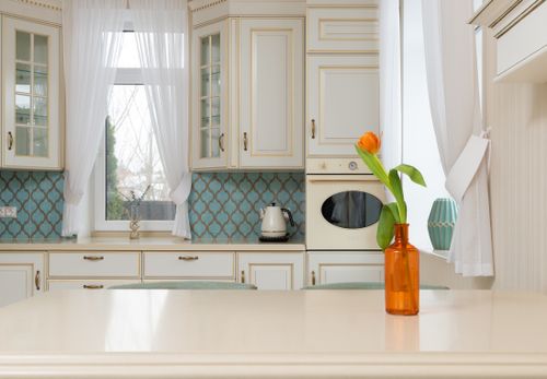 Free Interior of light empty kitchen with classic cabinets near wooden table with glass vase of tulips flower Stock Photo