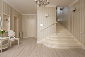 Interior of spacious cozy hallway with beige striped walls and light stairs and furniture