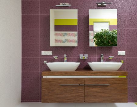 Interior of modern bathroom with double sink on wooden cabinet under mirrors hanging on bright wall