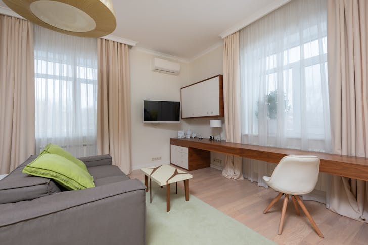 Interior of contemporary spacious living room with timber table and white chair on beige laminate
